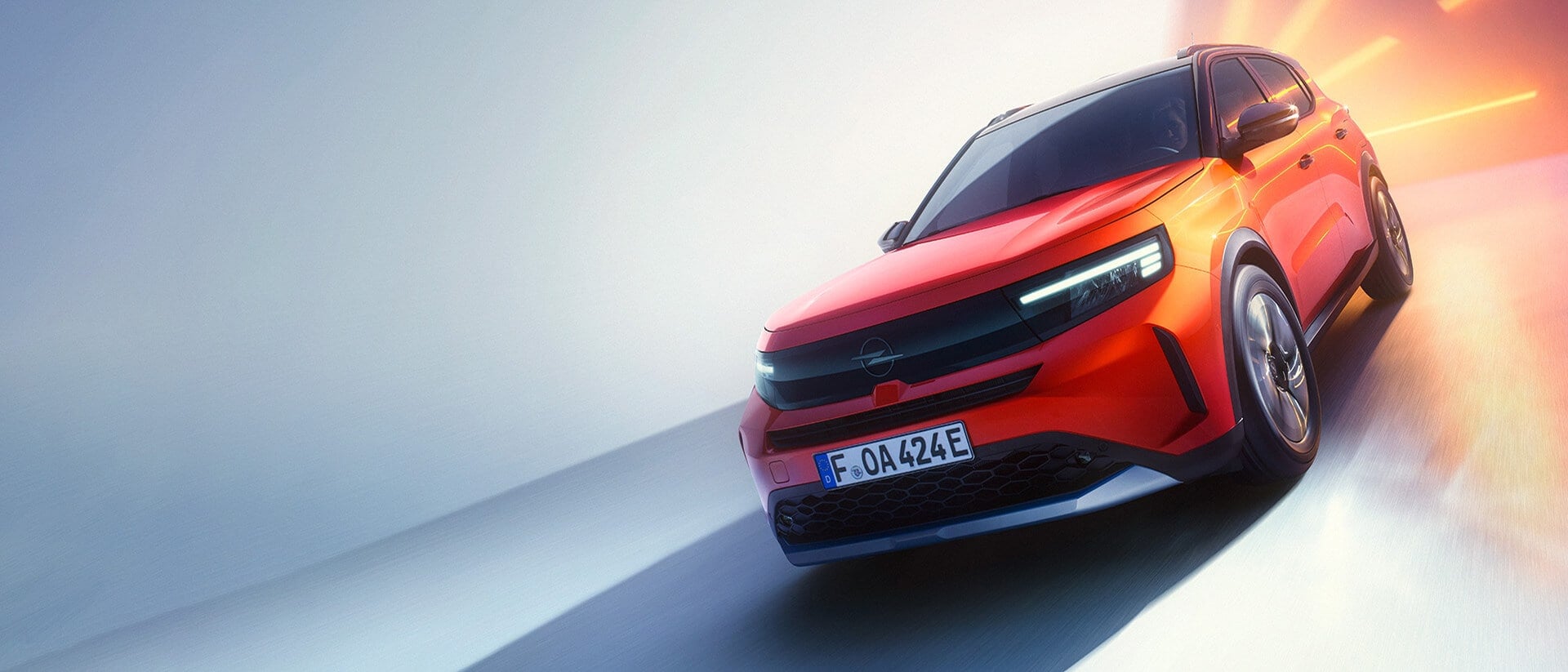 Ein rotes Auto fährt dynamisch auf einer Straße, die von weichem Licht in Blau- und Orangetönen beleuchtet wird. Das Fahrzeug hebt sich hervor, während es leicht geneigt ist und einen sportlichen Eindruck vermittelt.