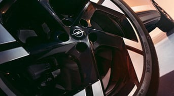Nahaufnahme eines schwarzen Autoreifens mit einer glänzenden Felge und dem Opel-Logo in der Mitte.